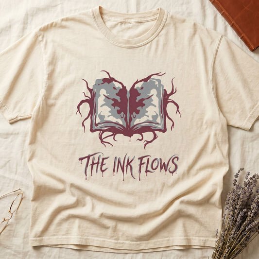 Ivory tee with open book bleeding red ink into a gray face on green ground, "THE INK FLOWS" in dripping serif.