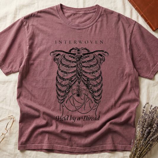 Dark Rose tee with cream skeletal ribcage suspended by trailing threads, "Held by a Thread" in serif on plate below.