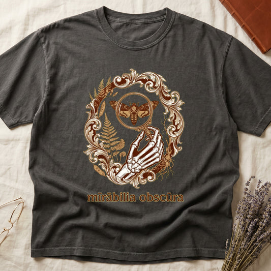 Pepper tee with skeletal hand, magnifying glass, death's-head moth, ferns on green, "mīrābilia obscūra" in Latin italic.
