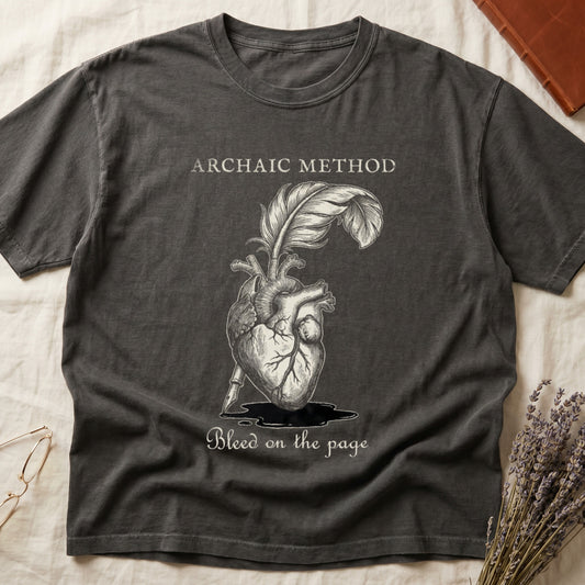 Pepper tee with anatomical heart and quill emerging in cream linework, "ARCHAIC METHOD" top, "Bleed on the page" below.