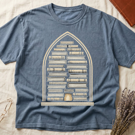 Blue Jean tee with gothic arch frame, columns of leather-bound books inside, sunburst medallion at base, cream engraved linework.