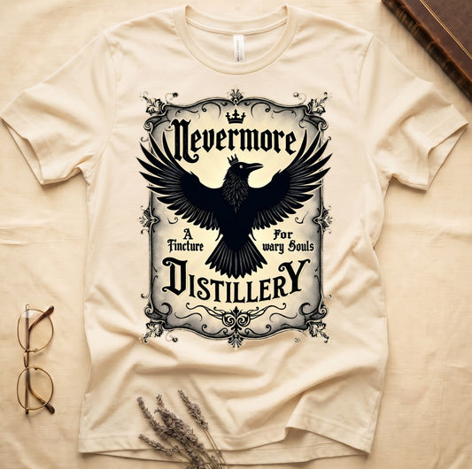 Natural tee with antique label, crowned raven, blackletter "Nevermore" top, "A Tincture For wary Souls," "DISTILLERY" bottom.