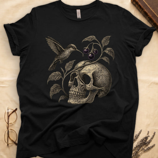 Black tee with sepia engraved skull, nightshade vine and dark-purple berries wrapping around, hummingbird at upper left.