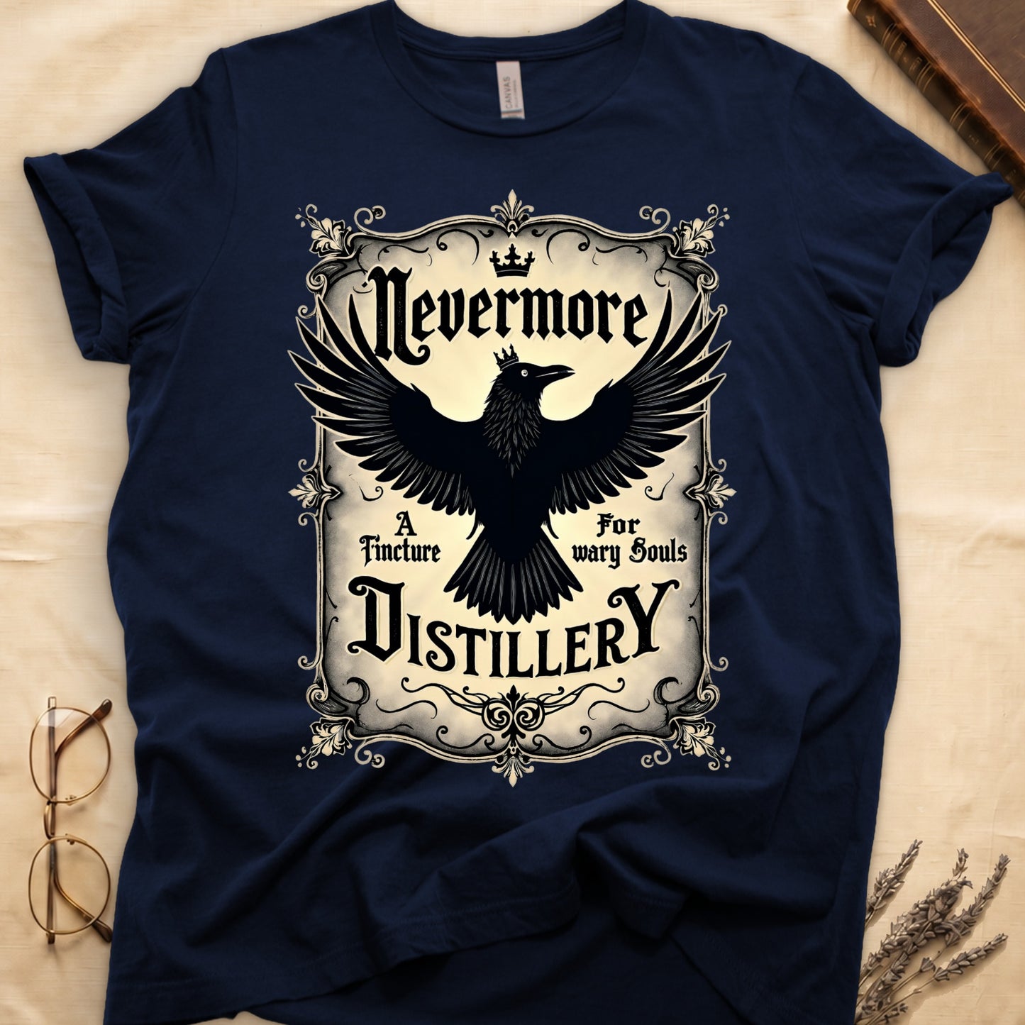 Navy tee with antique label, crowned raven, blackletter "Nevermore" top, "A Tincture For wary Souls," "DISTILLERY" bottom.