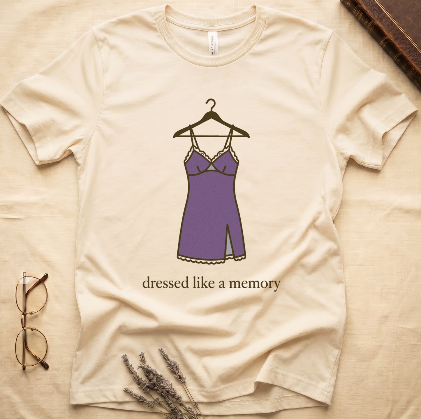 Natural tee with dusty plum slip dress on cream hanger and "dressed like a memory" in lowercase cream serif below.