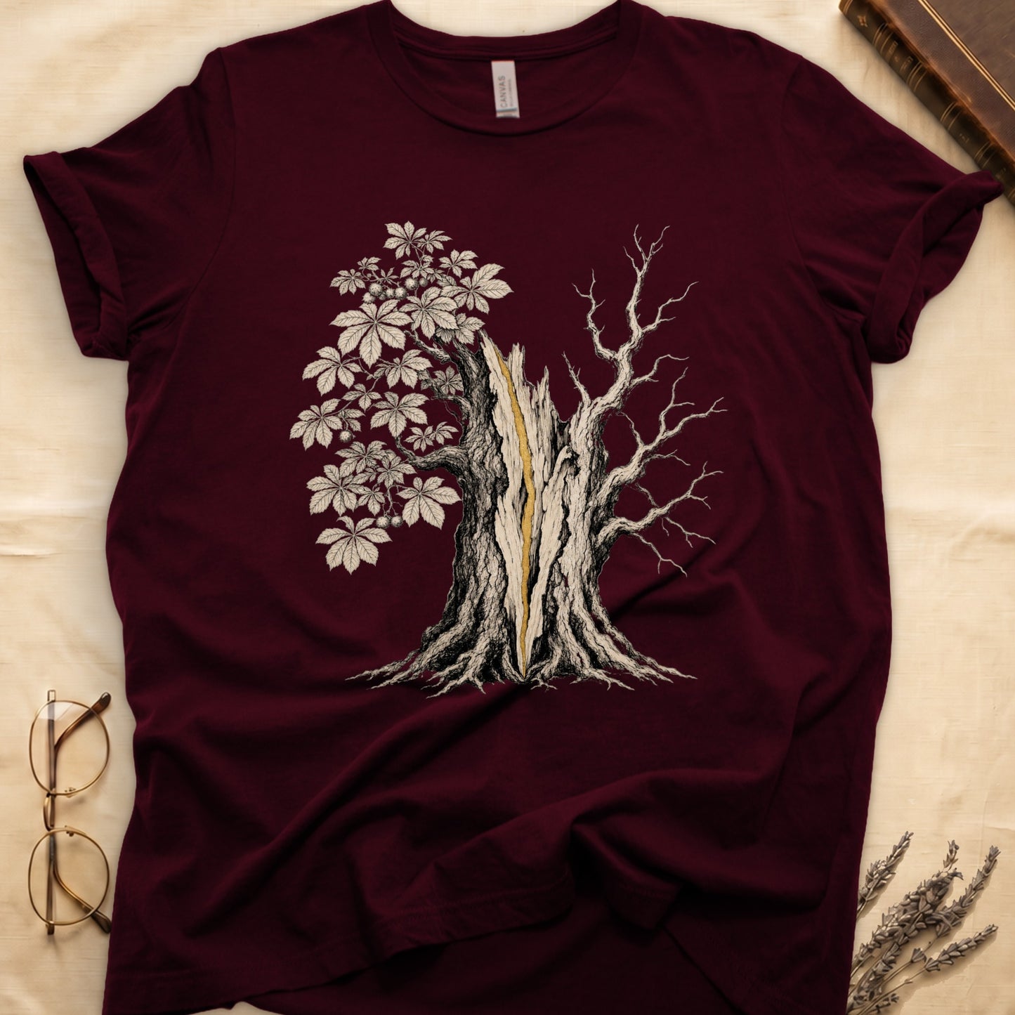 Maroon t-shirt with a detailed illustration of a split tree with leaves on one side and bare branches on the other.