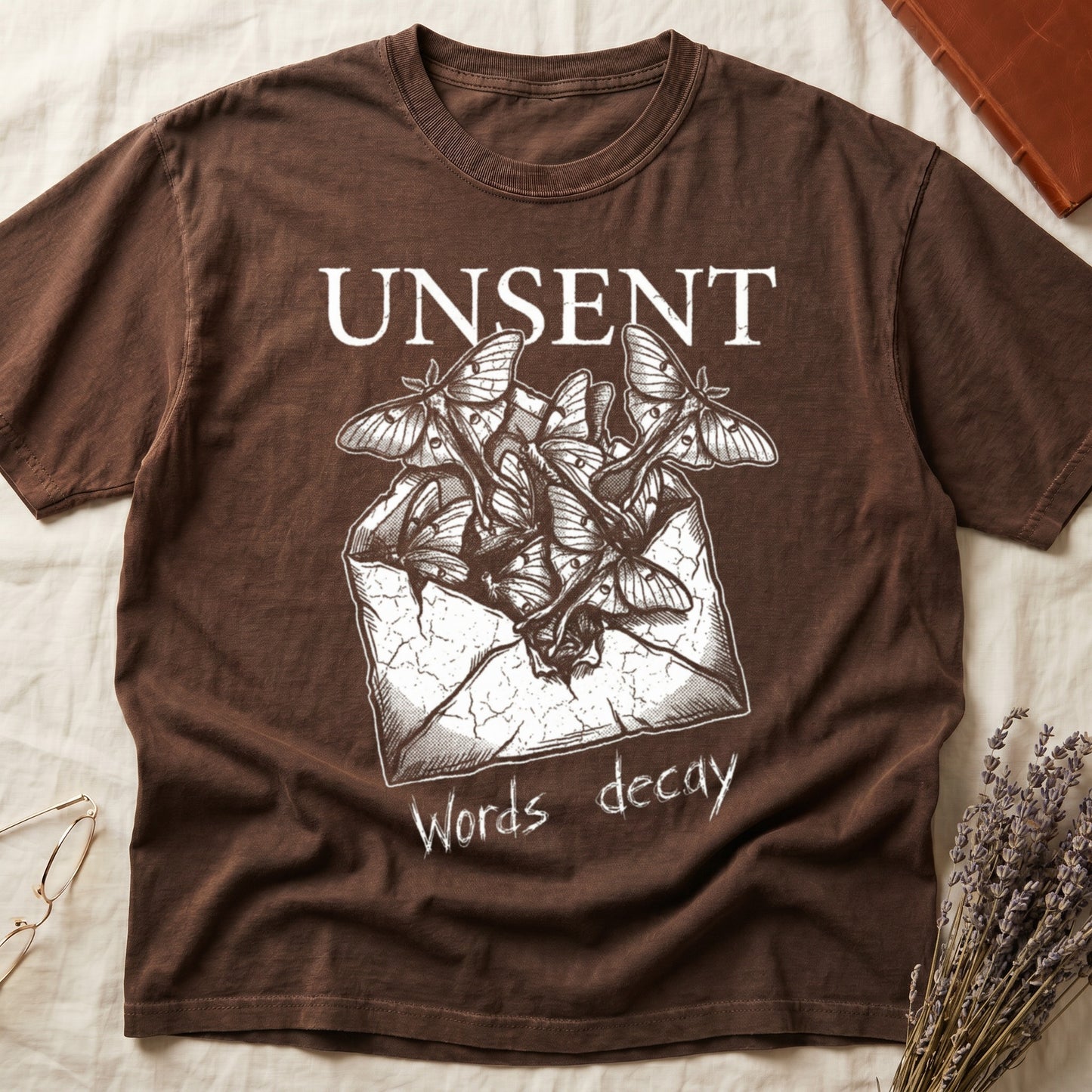 Espresso tee with 'UNSENT' in serif type, 'Words decay' brush text, luna moths from torn envelope in crosshatched ink