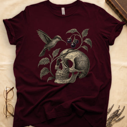 Maroon tee with sepia engraved skull, nightshade vine and dark-purple berries wrapping around, hummingbird at upper left.