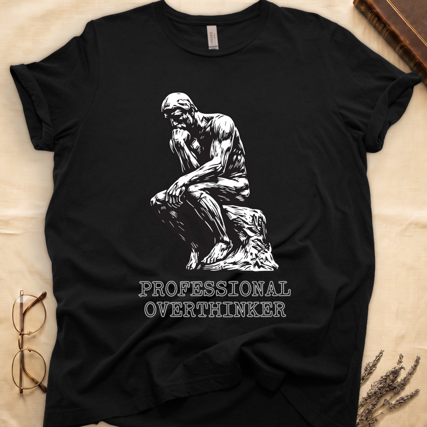 Black tee with monochrome rendering of Rodin's Thinker, "PROFESSIONAL OVERTHINKER" in serif capitals below.