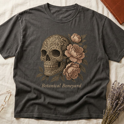 Pepper tee with filigree-engraved skull on left, peach-cream peonies on right, crossed bones below, "Botanical Boneyard."