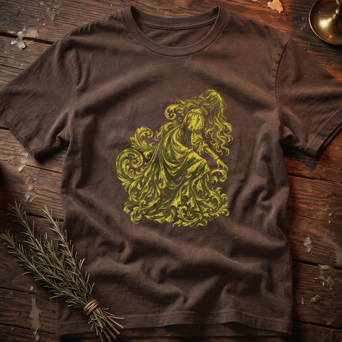 Brown t-shirt with a green ornate illustration of a figure with flowing hair and a dress.