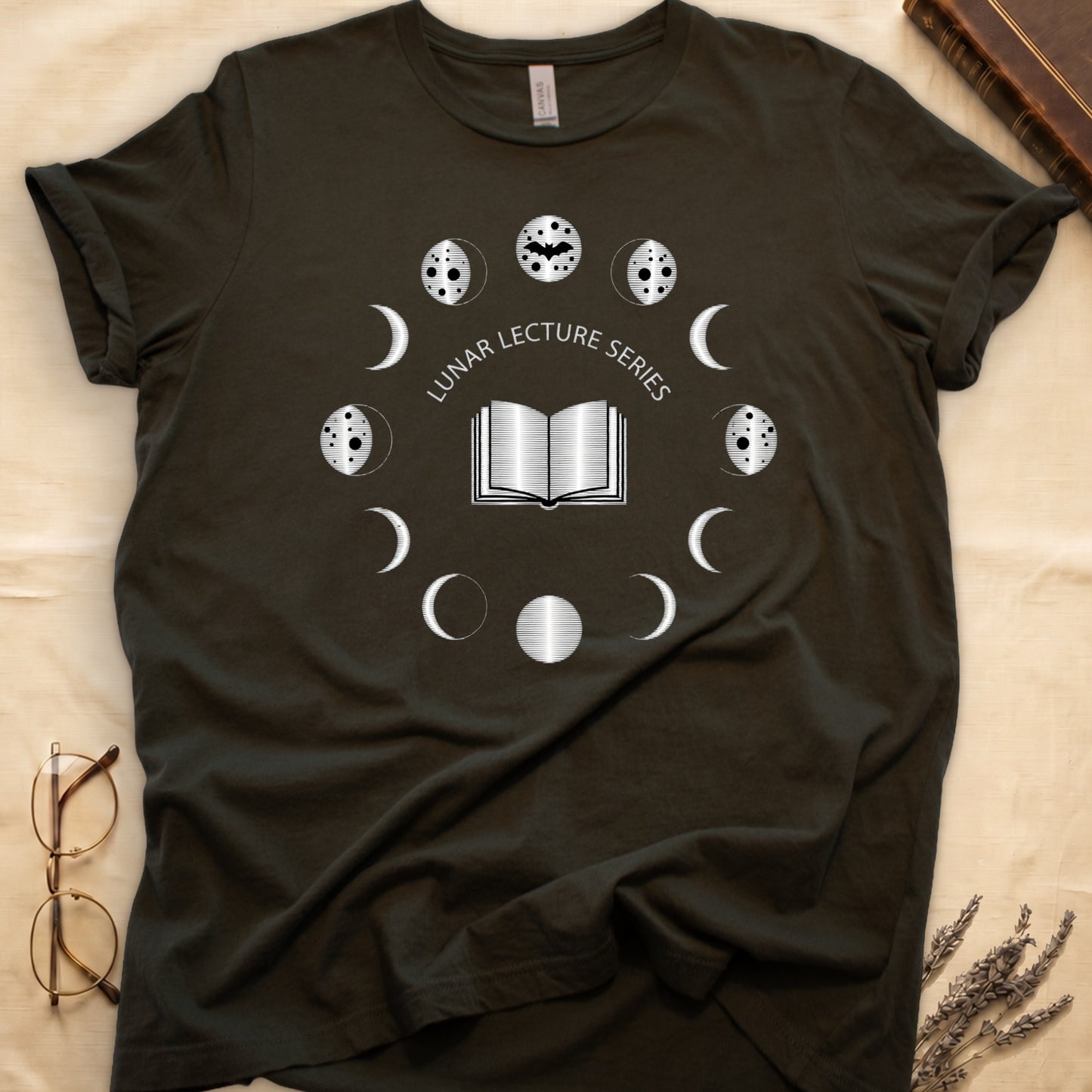 Military Green tee with open book at center, ring of cream moon phases around, curved "LUNAR LECTURE SERIES" double-arc above.
