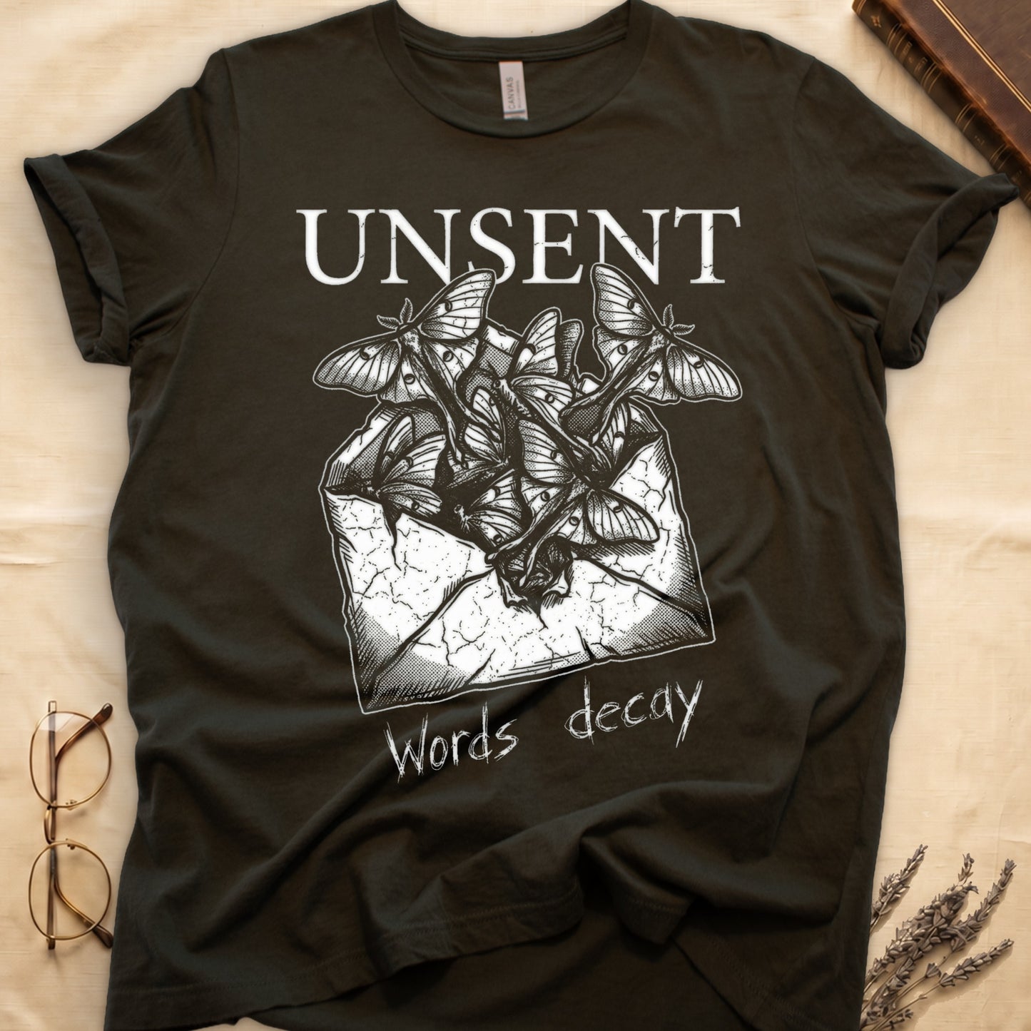Military Green tee with 'UNSENT' in serif type, 'Words decay' brush text, luna moths from torn envelope in crosshatched ink