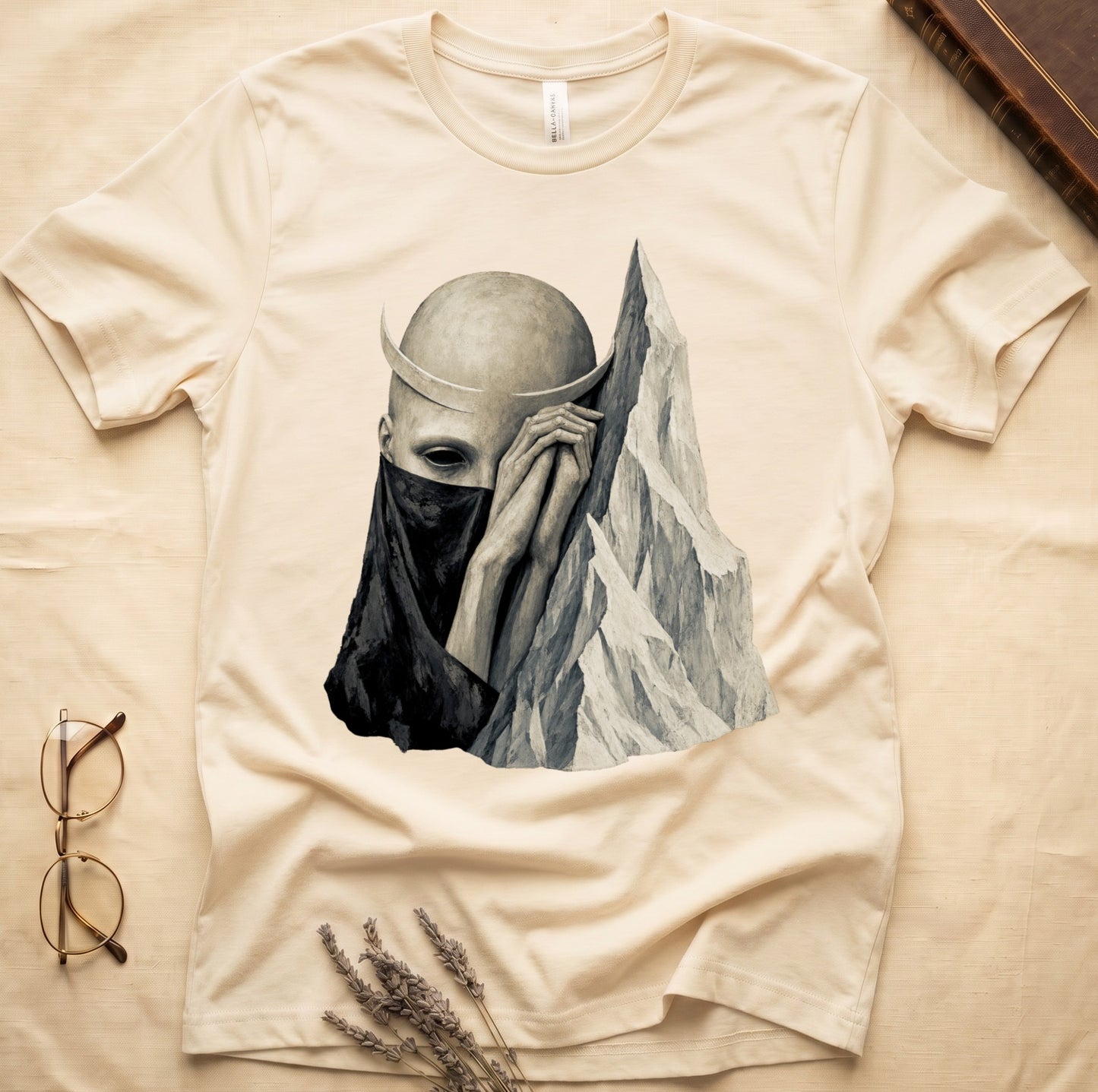 Cream t-shirt with surrealist print of a masked figure and mountains.