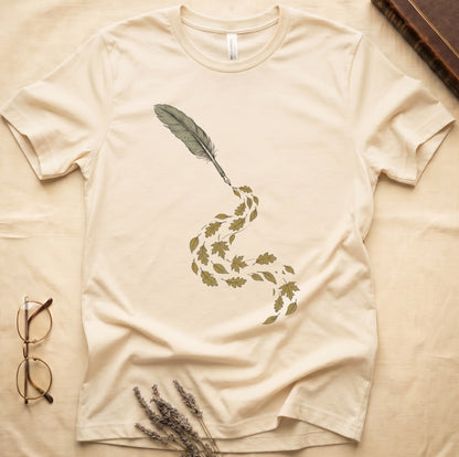Natural tee with antique quill pen in cream linework, oak and maple leaves cascading from the nib in gold and green.