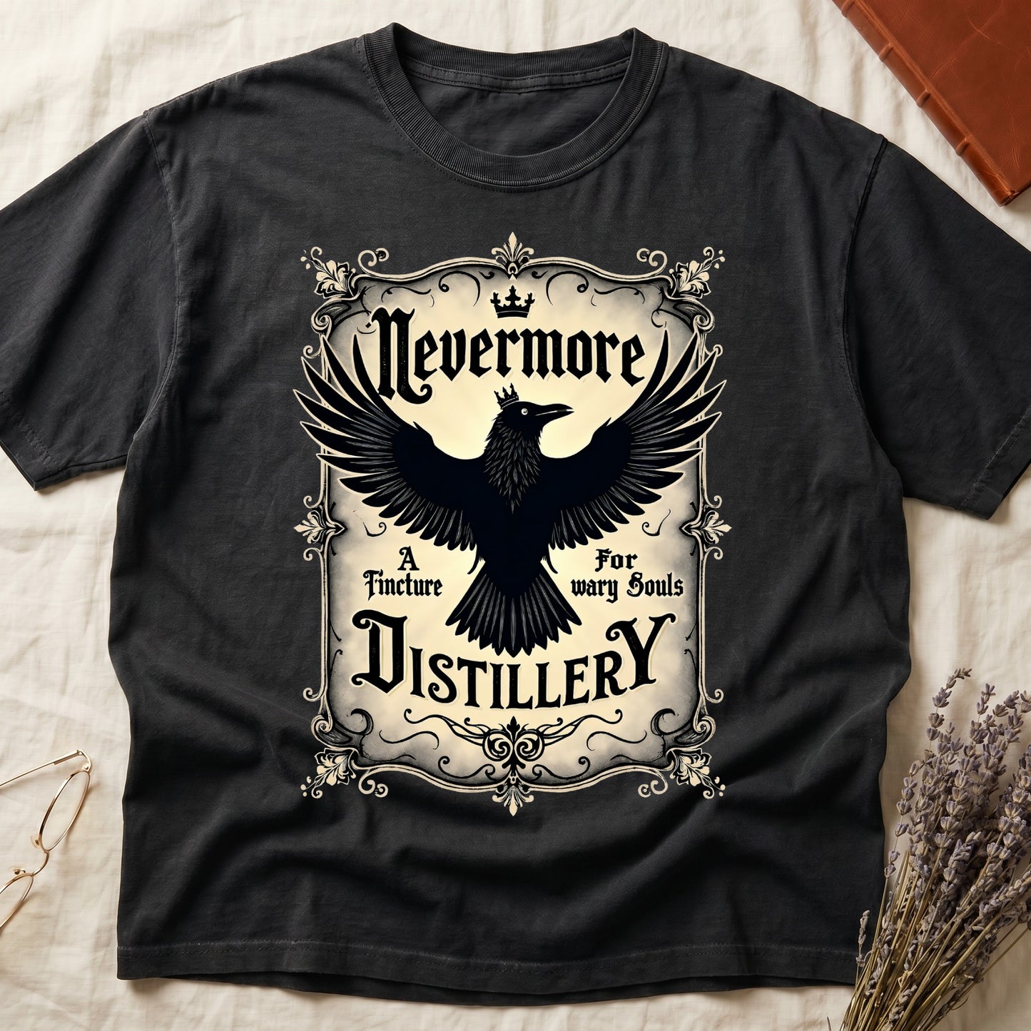 Black tee with antique label, crowned raven, blackletter "Nevermore" top, "A Tincture For wary Souls," "DISTILLERY" bottom.