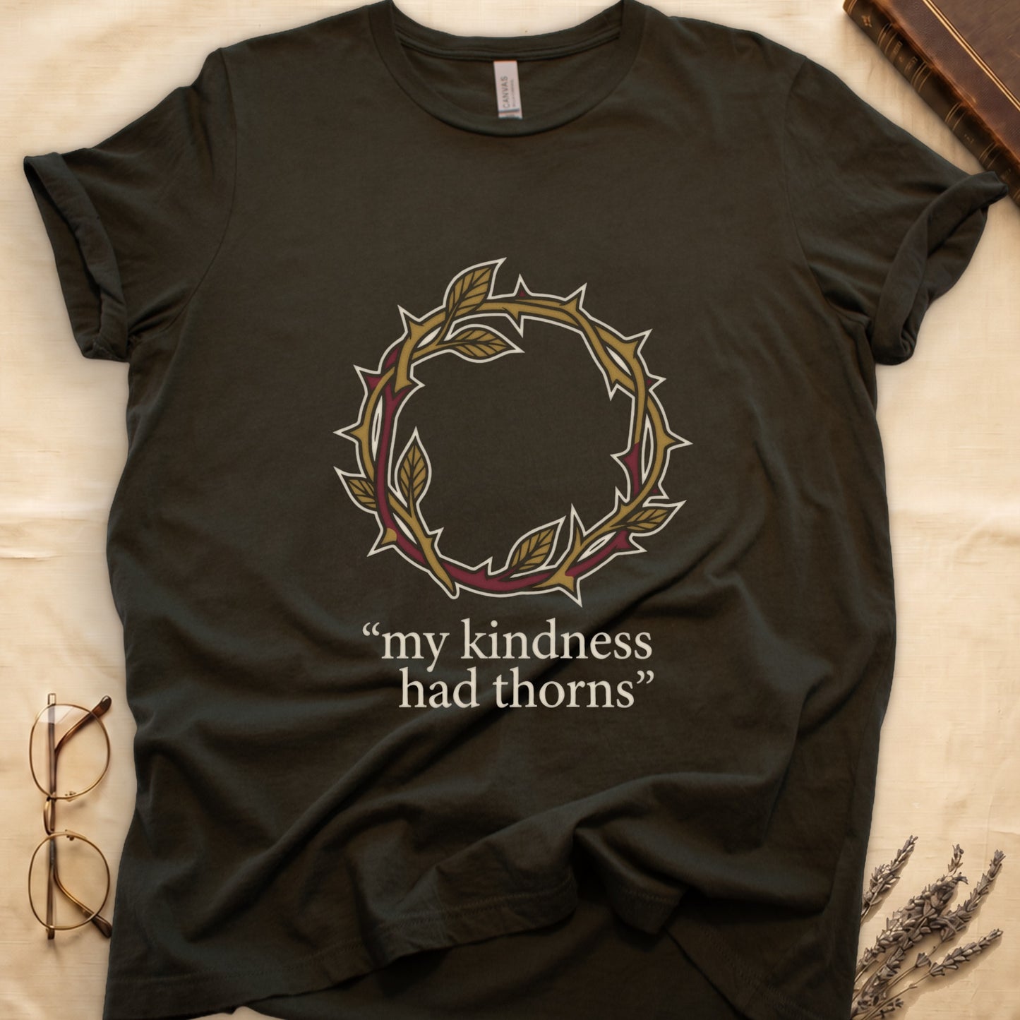 Military Green tee with crown of thorns in gold and red with green leaves, "my kindness had thorns" in cream serif.