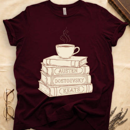 Maroon tee with stack of vintage books labeled "AUSTEN," "DOSTOEVSKY," "KEATS" topped with a steaming coffee cup.