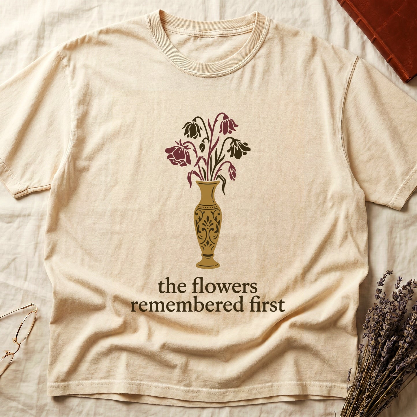 Ivory tee with gold ornate vase, wilting cream lilies and dark red roses, "the flowers remembered first" in cream serif.
