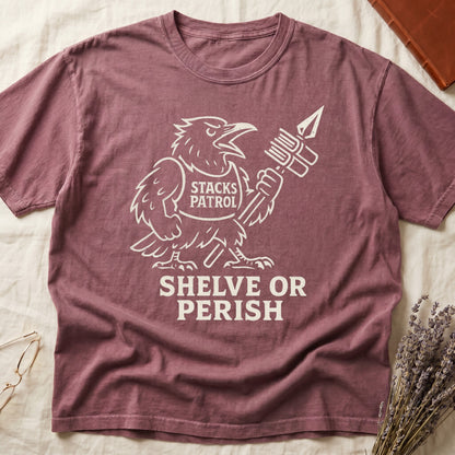 Dark Rose tee with vintage raven mascot, "STACKS PATROL" sash, feather pen aloft, "SHELVE OR PERISH" bold serif below.