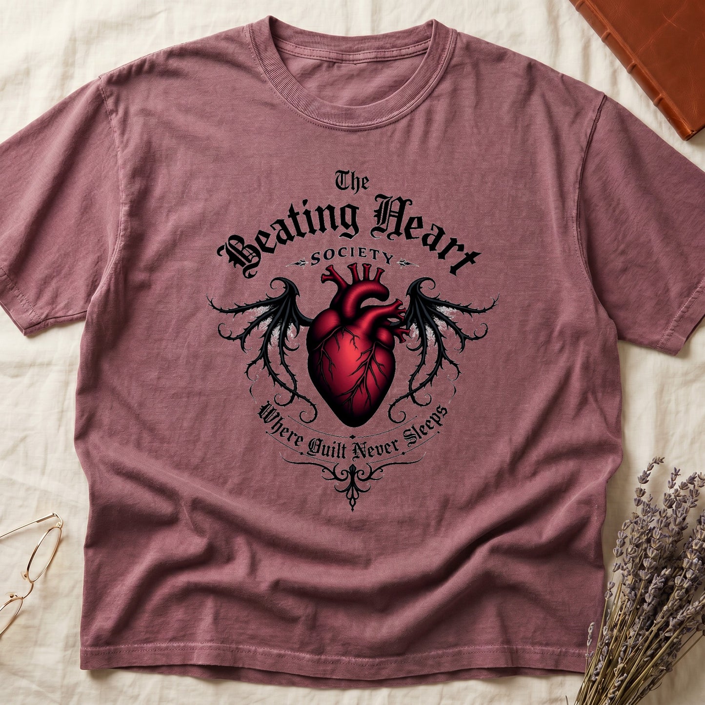 Dark Rose tee with anatomical red heart, gothic wings, "The Beating Heart SOCIETY," "Where Guilt Never Sleeps" below.