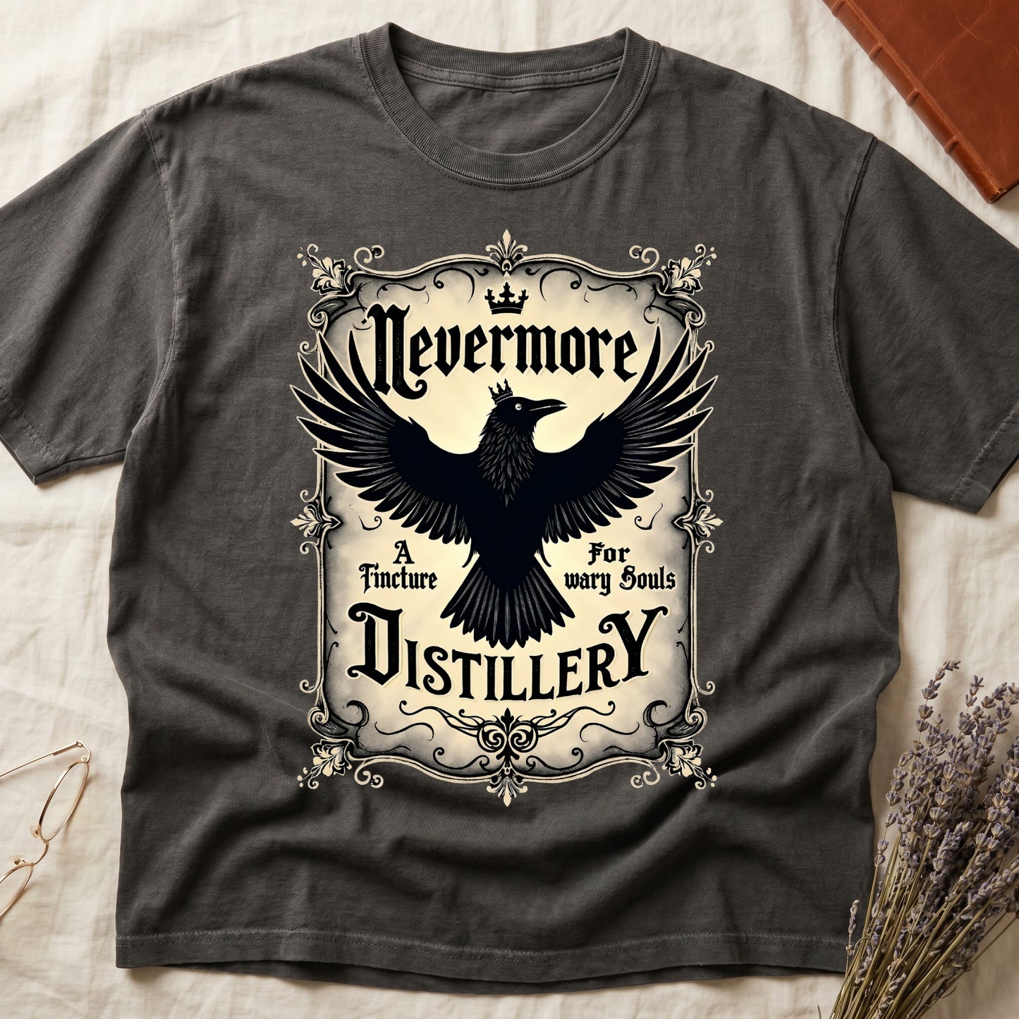 Pepper tee with antique label, crowned raven, blackletter "Nevermore" top, "A Tincture For wary Souls," "DISTILLERY" bottom.