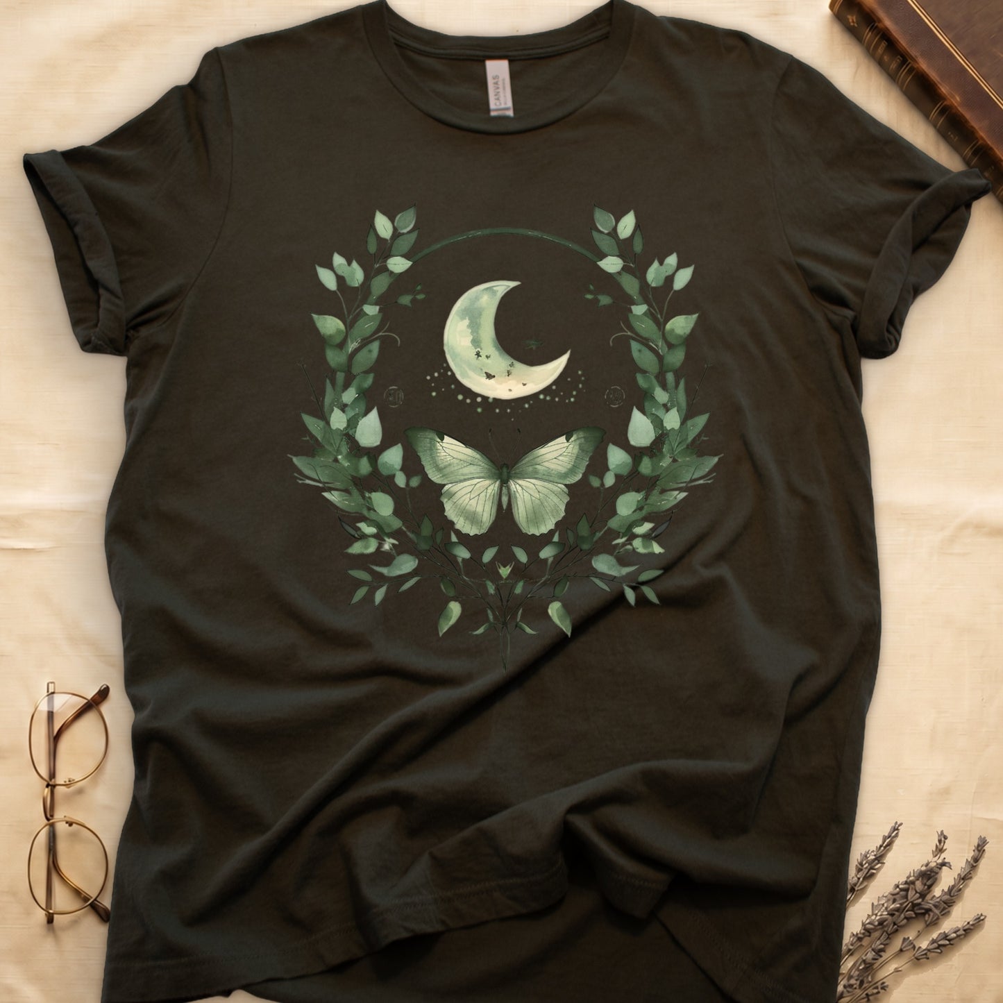 Dark green t-shirt with a crescent moon, butterfly, and green leaves design.