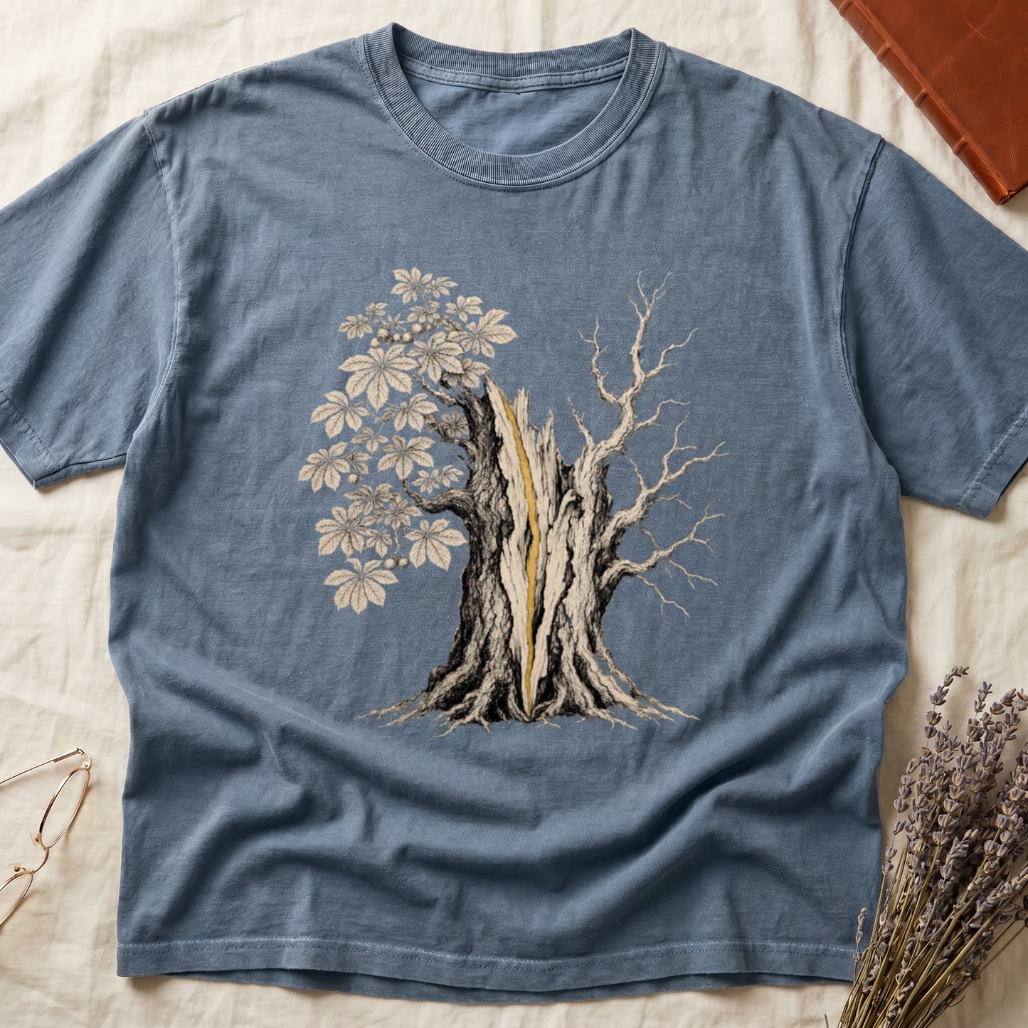 Blue t-shirt with a graphic of a split tree with leaves and bare branches.