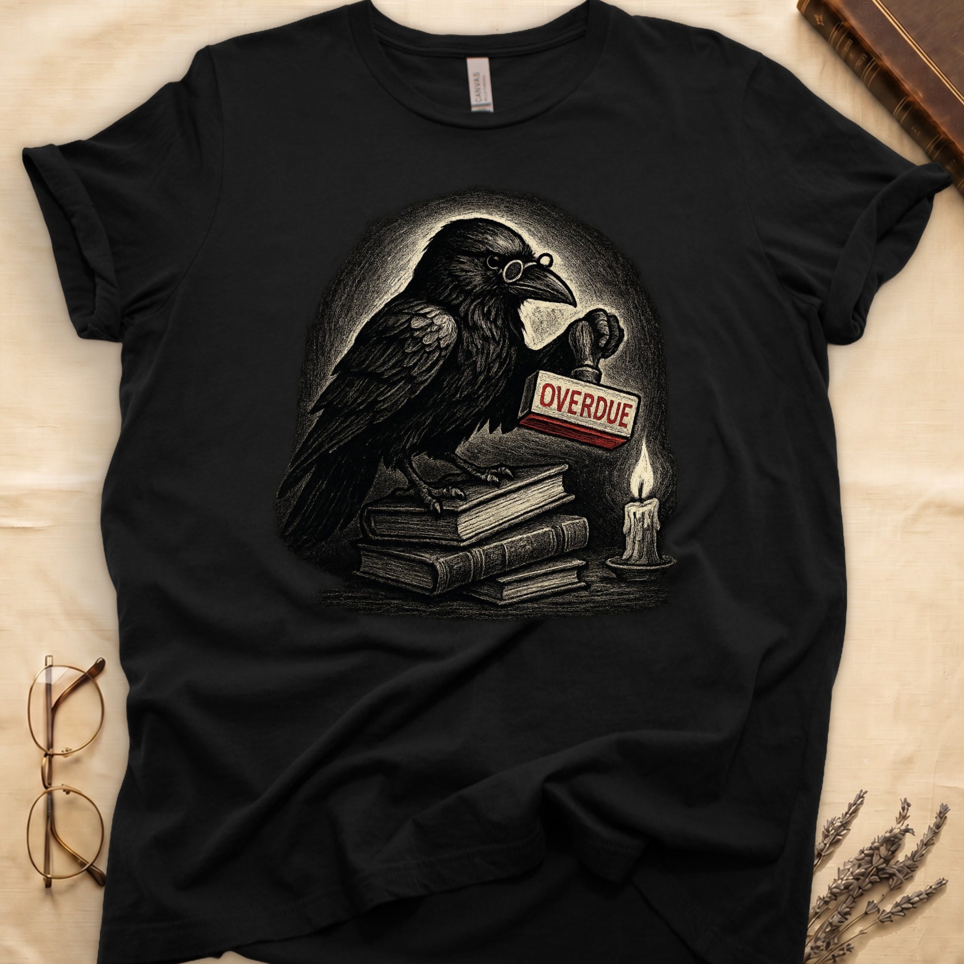 Black tee with bespectacled raven on stacked books, holding wooden "OVERDUE" stamp, lit candle beside, dawn glow behind.