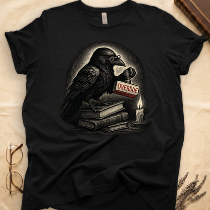 Black tee with bespectacled raven on stacked books, holding wooden "OVERDUE" stamp, lit candle beside, dawn glow behind.