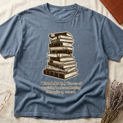 Blue Jean tee with stack of vintage hardcovers, "Tsundoku (n.) The act of acquiring books and letting them pile up unread."