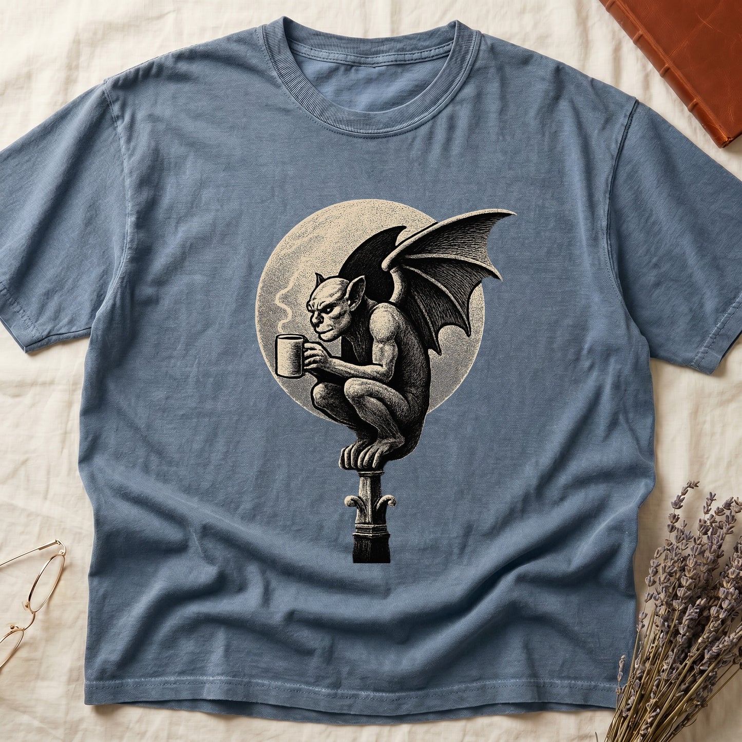 Blue Jean tee with gargoyle on stone pinnacle holding coffee mug, cream-parchment full moon behind, engraving style.