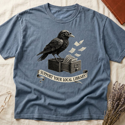 Espresso tee with raven writing on "823.4" parchment by candlelight, ink jar beside, "MIDNIGHT CATALOGUER" banner above.