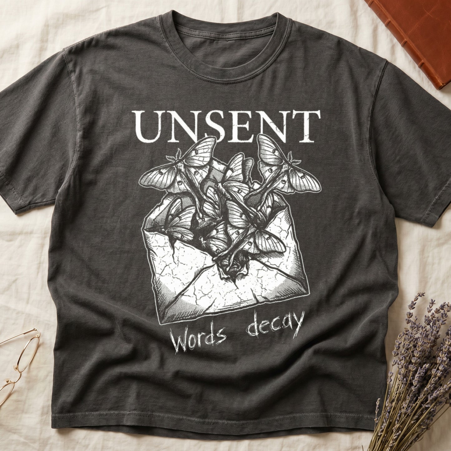 Pepper tee with 'UNSENT' in serif type, 'Words decay' brush text, luna moths from torn envelope in crosshatched ink