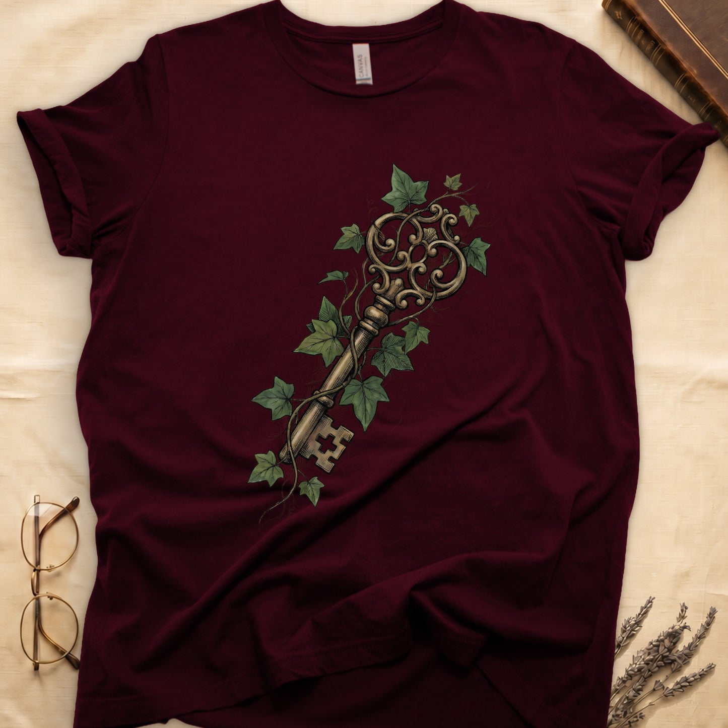 Maroon tee with ornate antique skeleton key in bronze, climbing English ivy in green on terracotta ground.