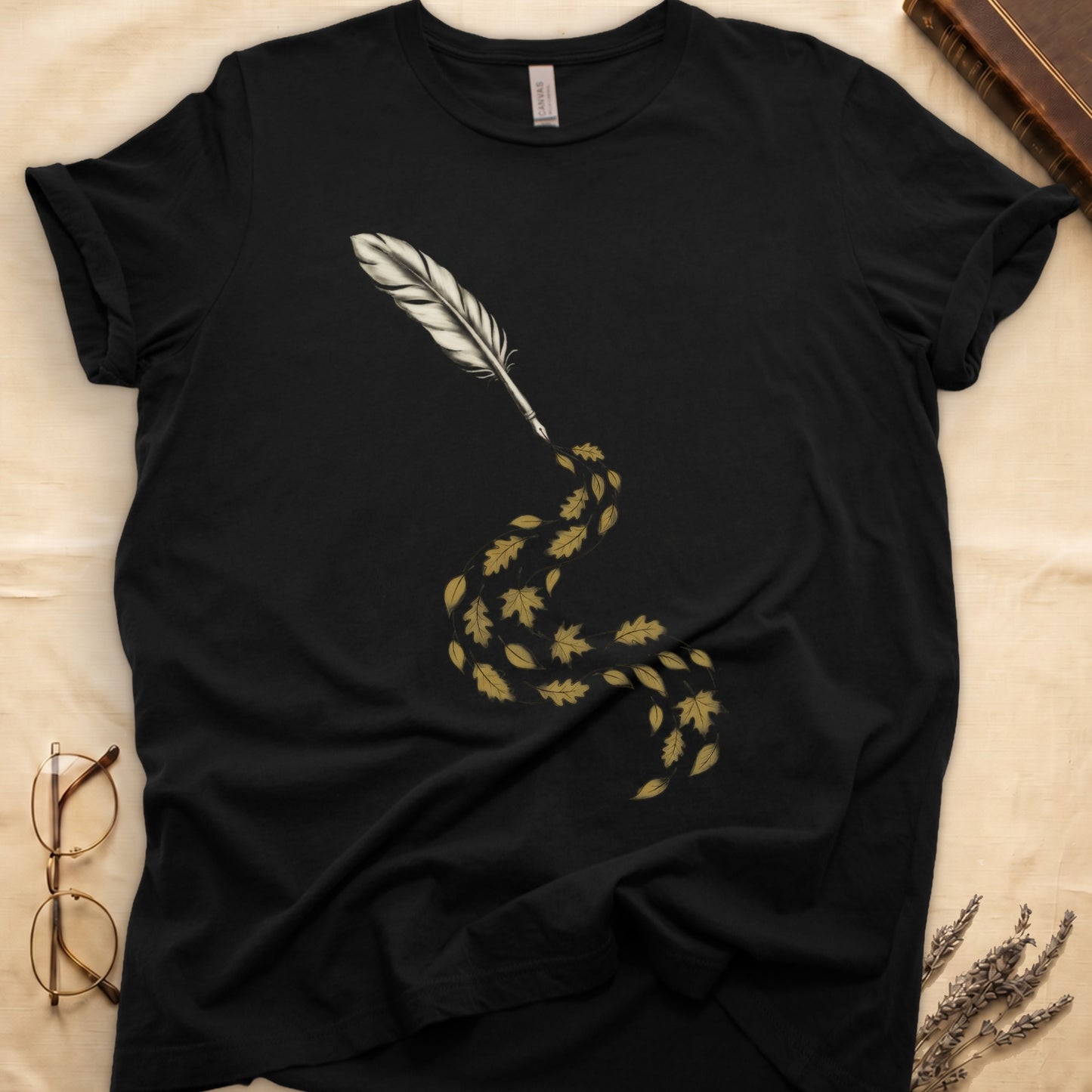 Black tee with antique quill pen in cream linework, oak and maple leaves cascading from the nib in gold and green.