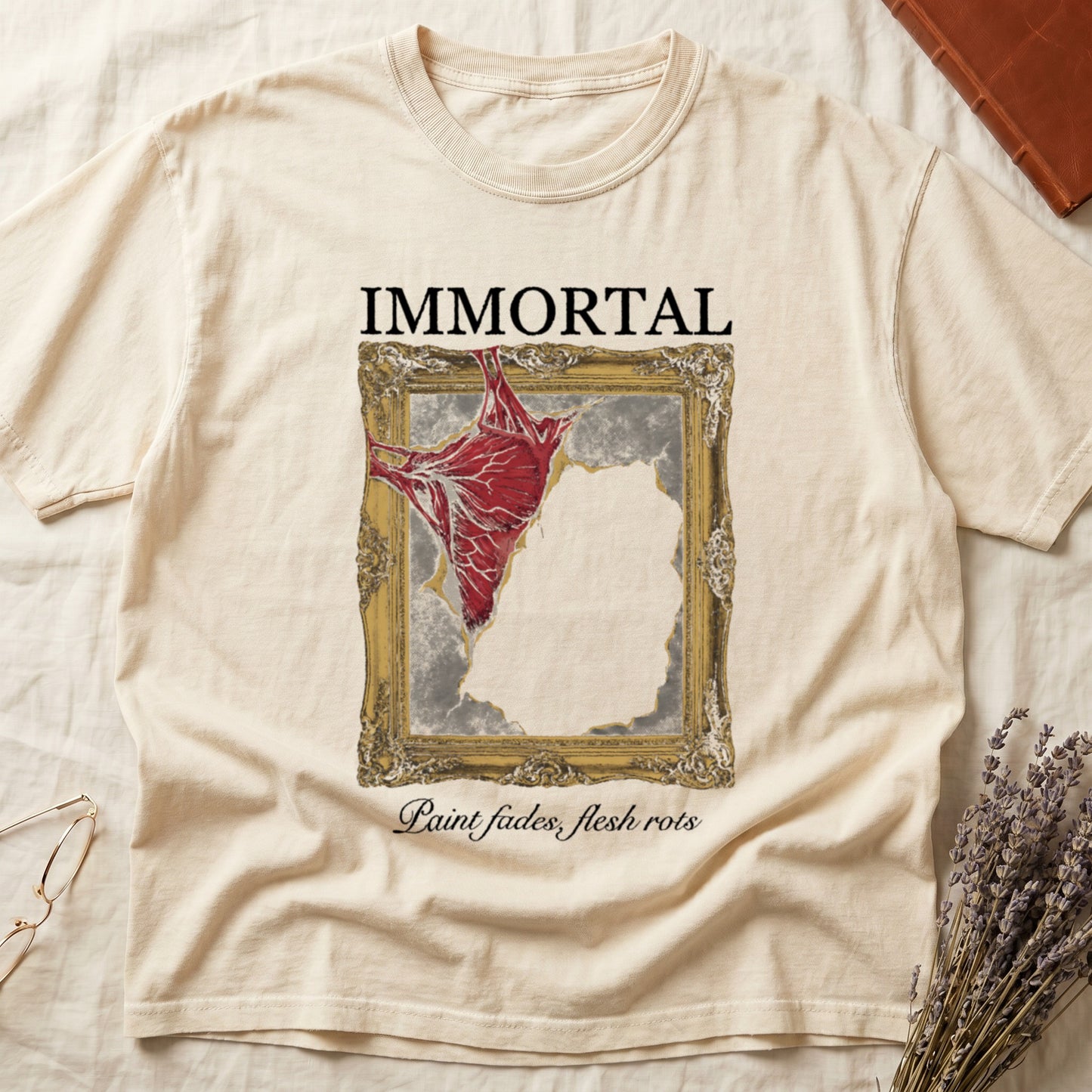 Ivory tee with gold frame and exposed muscle tearing canvas, "IMMORTAL" top, "Paint fades, flesh rots" italic below.