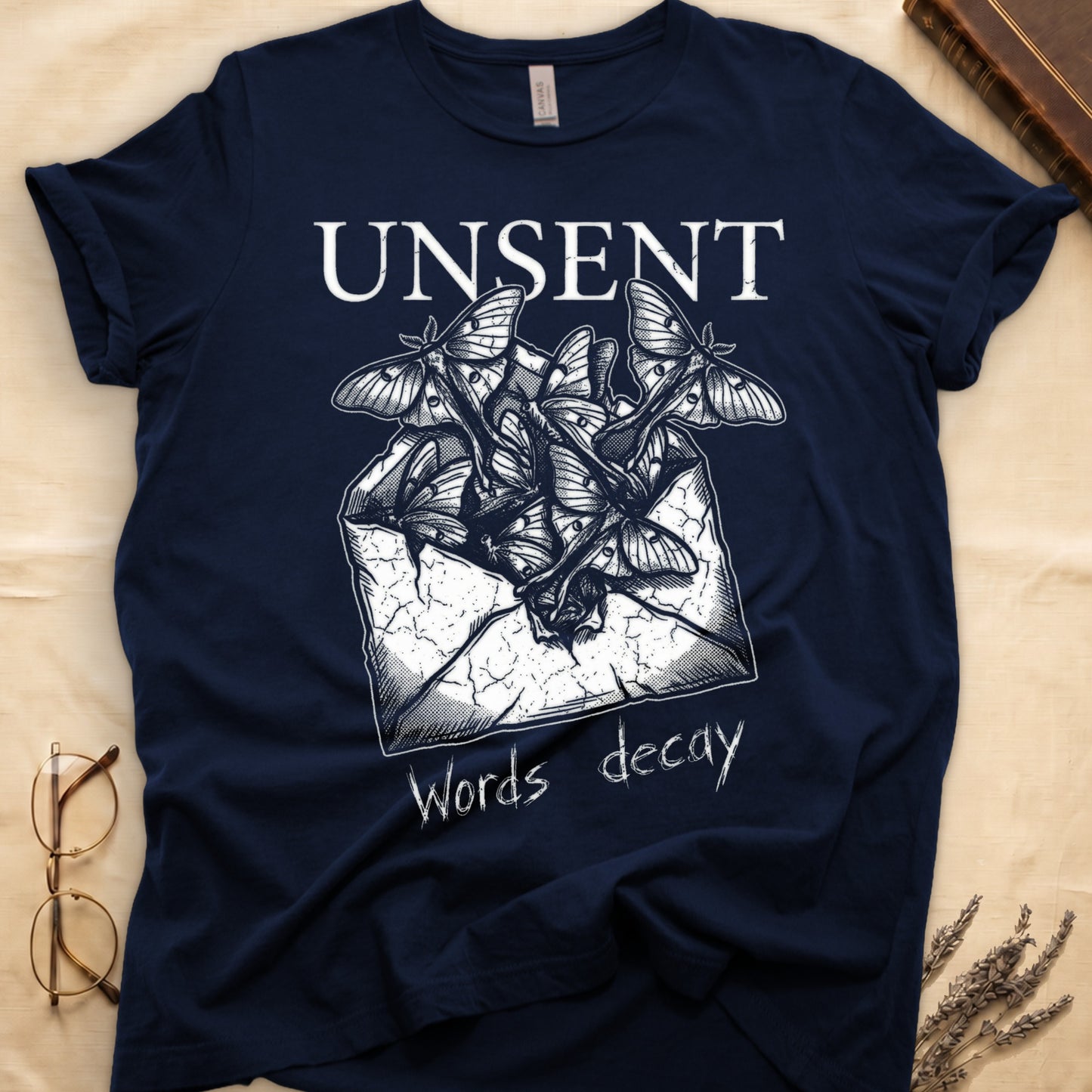 Navy tee with 'UNSENT' in serif type, 'Words decay' brush text, luna moths from torn envelope in crosshatched ink