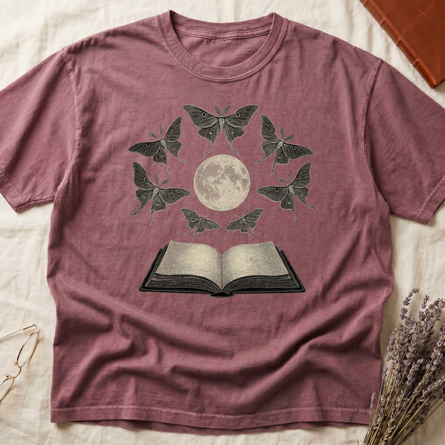 Dark Rose tee with full moon center, seven luna moths in halo around, open book below, cream-on-black engraving.