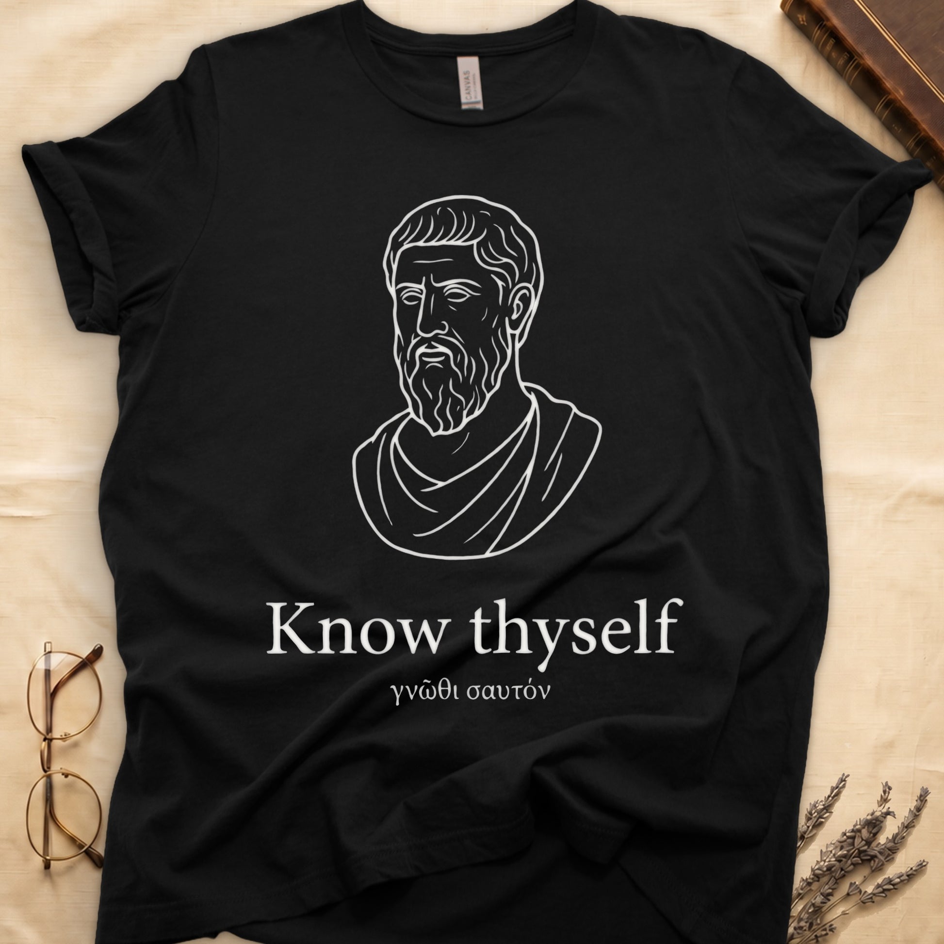 Black tee with classical Greek philosopher bust in white linework, "Know thyself" in cream serif below.