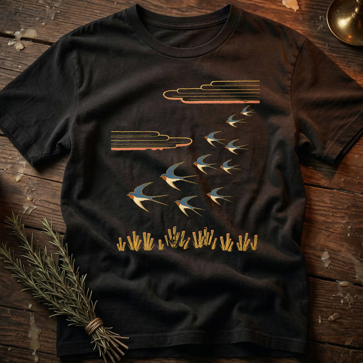 Black t-shirt with stylized flock of swallows flying above reeds and clouds.