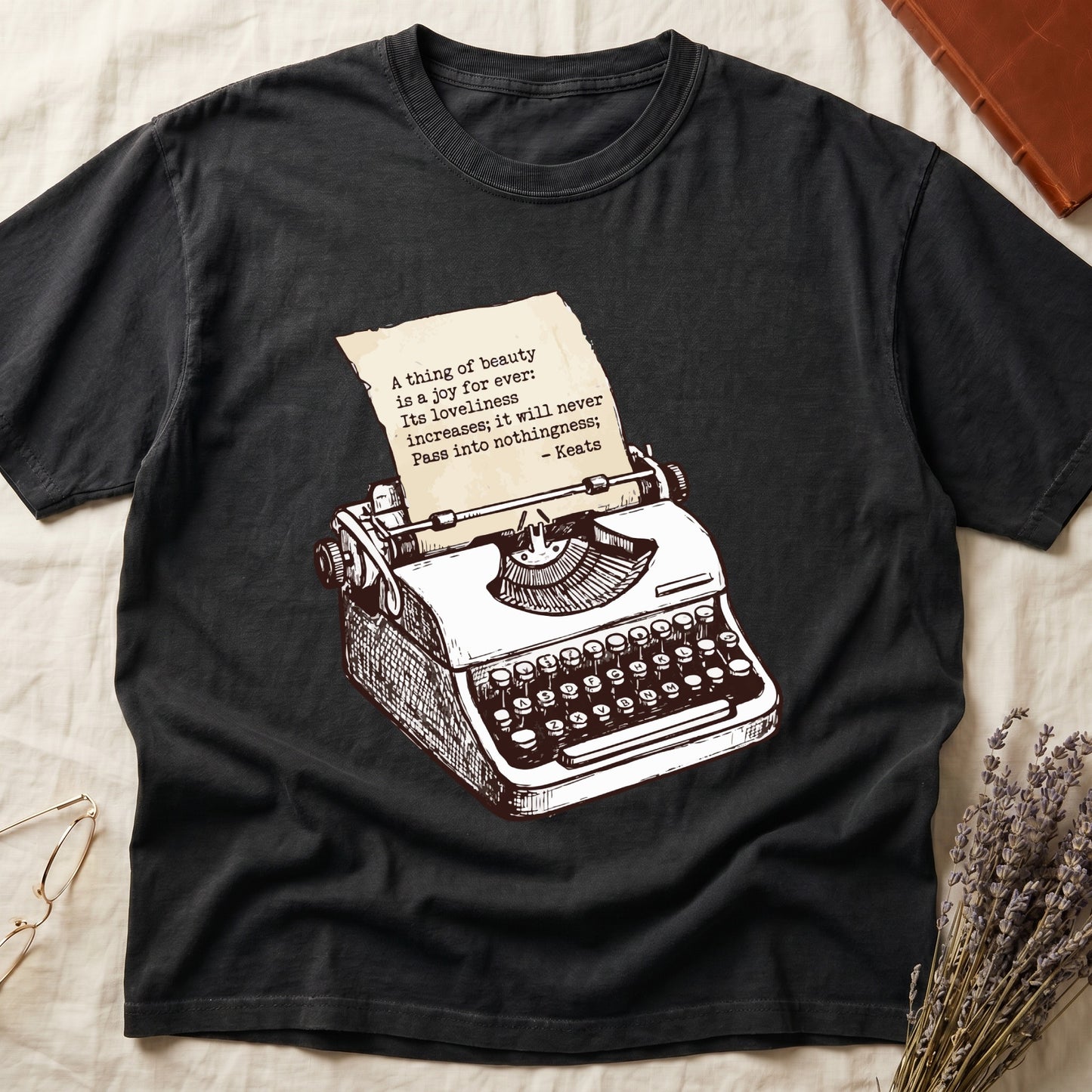 Black tee with vintage typewriter in cream linework, paper showing "A thing of beauty is a joy for ever" by Keats.
