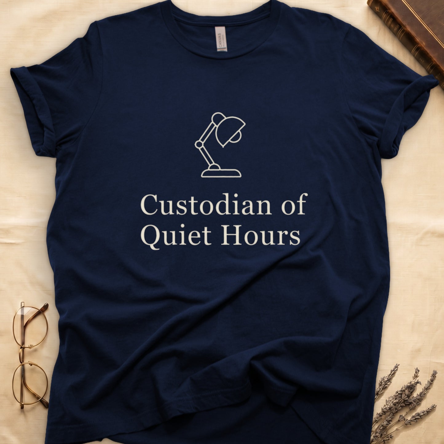 Navy tee with vintage desk lamp in cream linework above "Custodian of Quiet Hours" in distressed Art Deco caps.