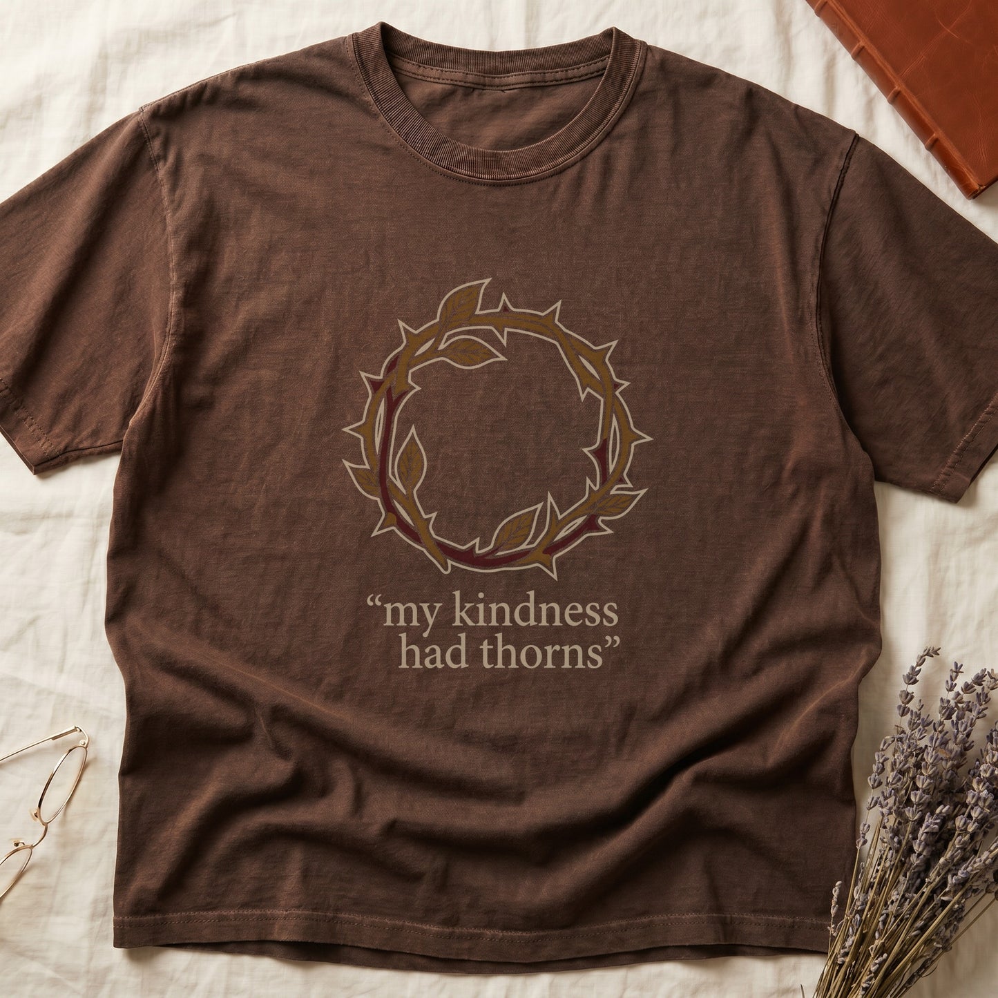 Espresso tee with crown of thorns in gold and red with green leaves, "my kindness had thorns" in cream serif.