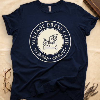 Navy tee with circular letterpress badge, "VINTAGE PRESS CLUB" in serif capitals, antique printing press in cream linework.