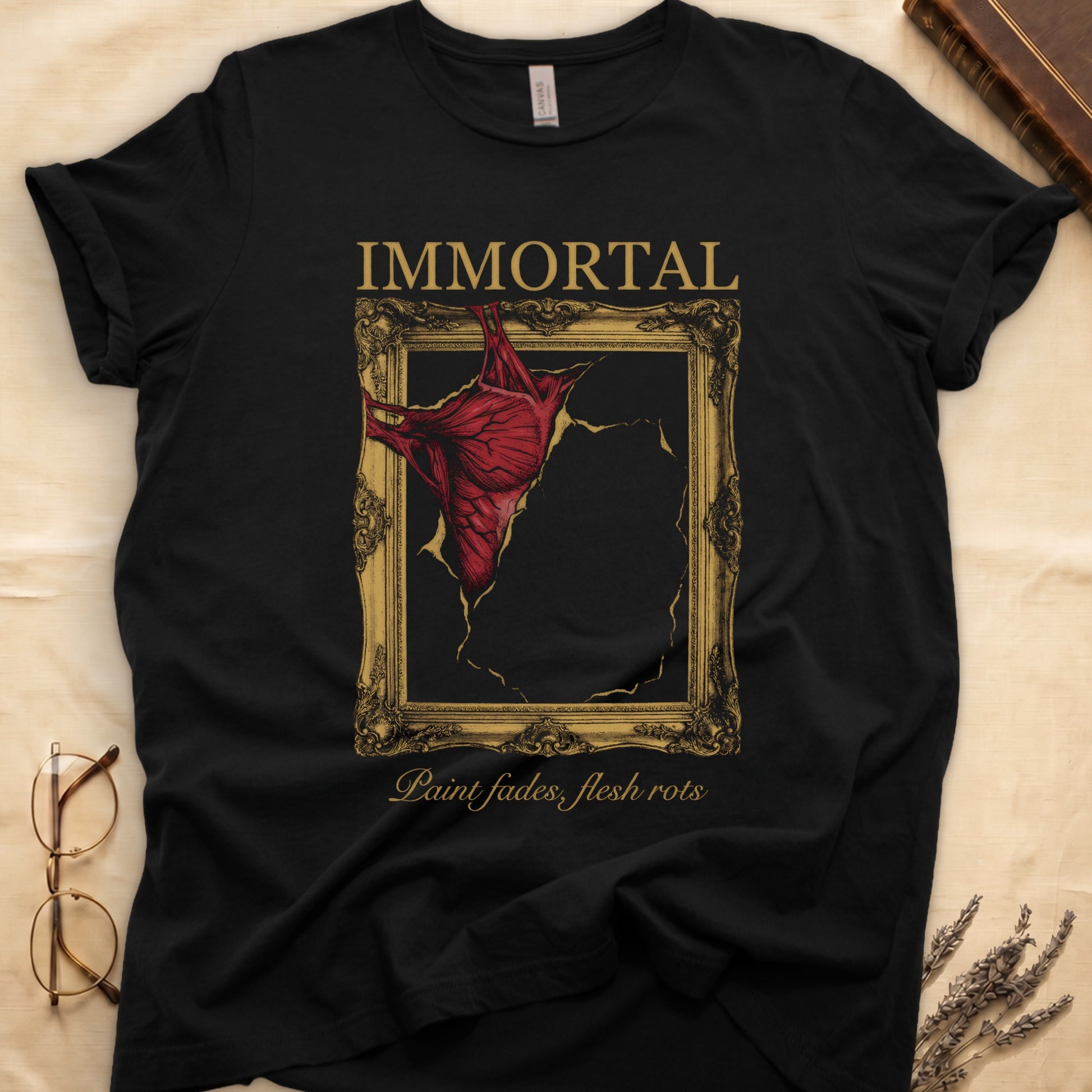 Black tee with gold frame and exposed muscle tearing canvas, "IMMORTAL" top, "Paint fades, flesh rots" italic below.