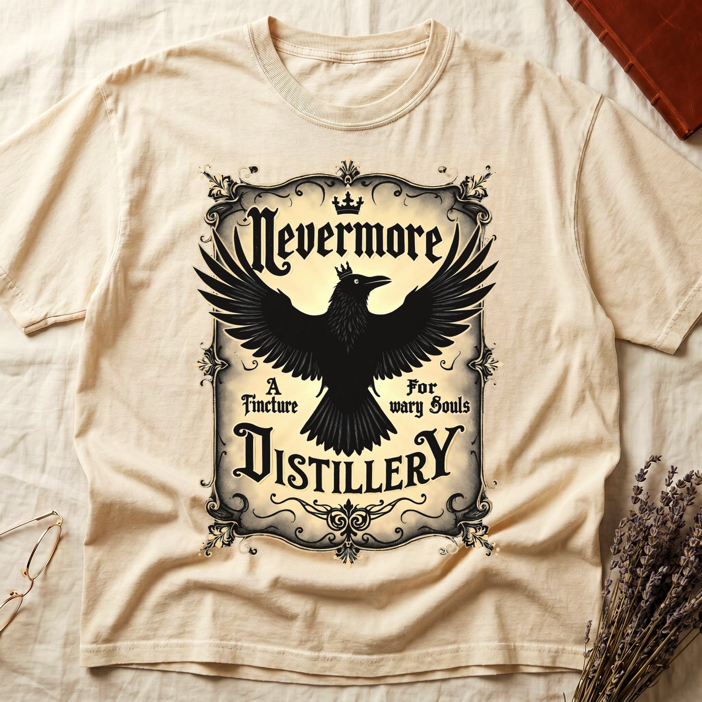 Ivory tee with antique label, crowned raven, blackletter "Nevermore" top, "A Tincture For wary Souls," "DISTILLERY" bottom.