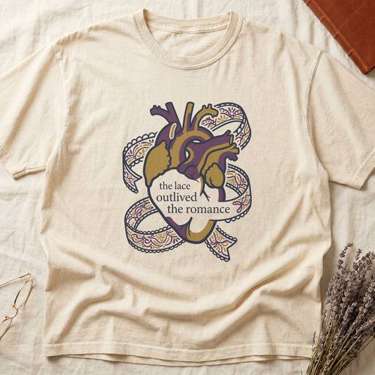 Ivory tee with anatomical heart in purple and gold wrapped in lace ribbons, "the lace outlived the romance" in serif.