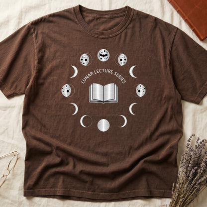 Espresso tee with open book at center, ring of cream moon phases around, curved "LUNAR LECTURE SERIES" double-arc above.