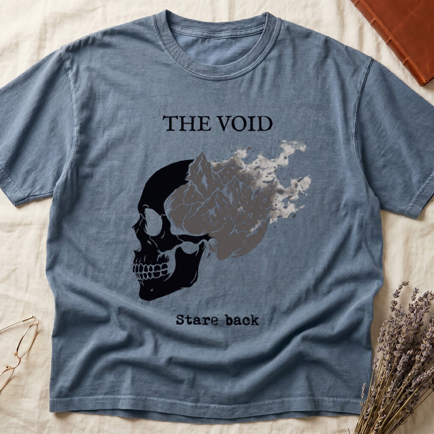 Blue Jean tee with skull eroding into mountain landscape and stardust, "THE VOID" top, "Stare back" typewriter below.
